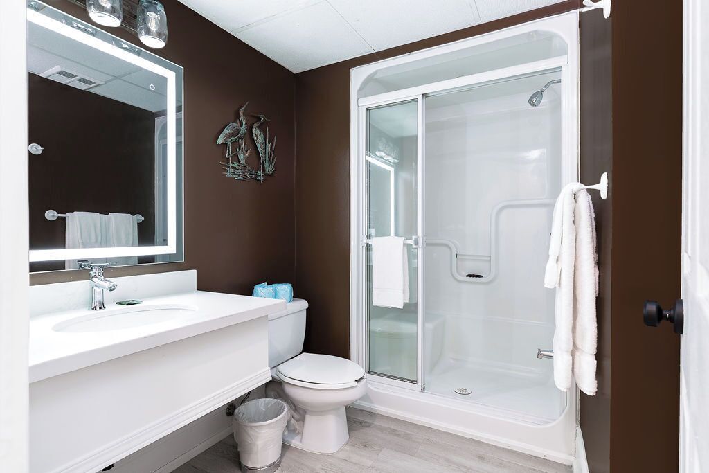 Un baño con lavamanos blanco, inodoro y ducha con mampara de vidrio.