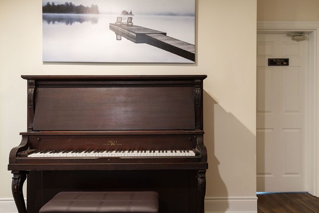 Um piano de cauda em um quarto com um quadro tranquilo de um píer que se estende sobre um lago nevoento.