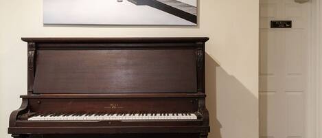 Um piano de cauda em um quarto com um quadro tranquilo de um píer que se estende sobre um lago nevoento.
