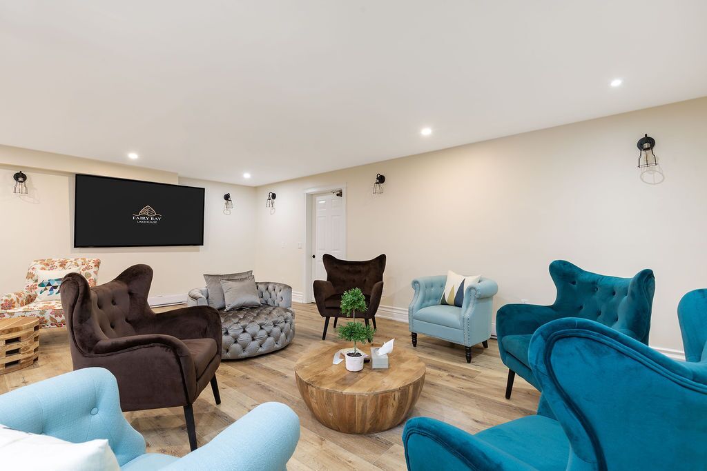 Un salon moderne avec une table basse ronde, plusieurs canapés et un téléviseur fixé au mur.