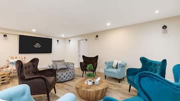 Ein modernes Wohnzimmer mit einem runden Couchtisch, mehreren Sofas und einem an der Wand befestigten Fernseher.
