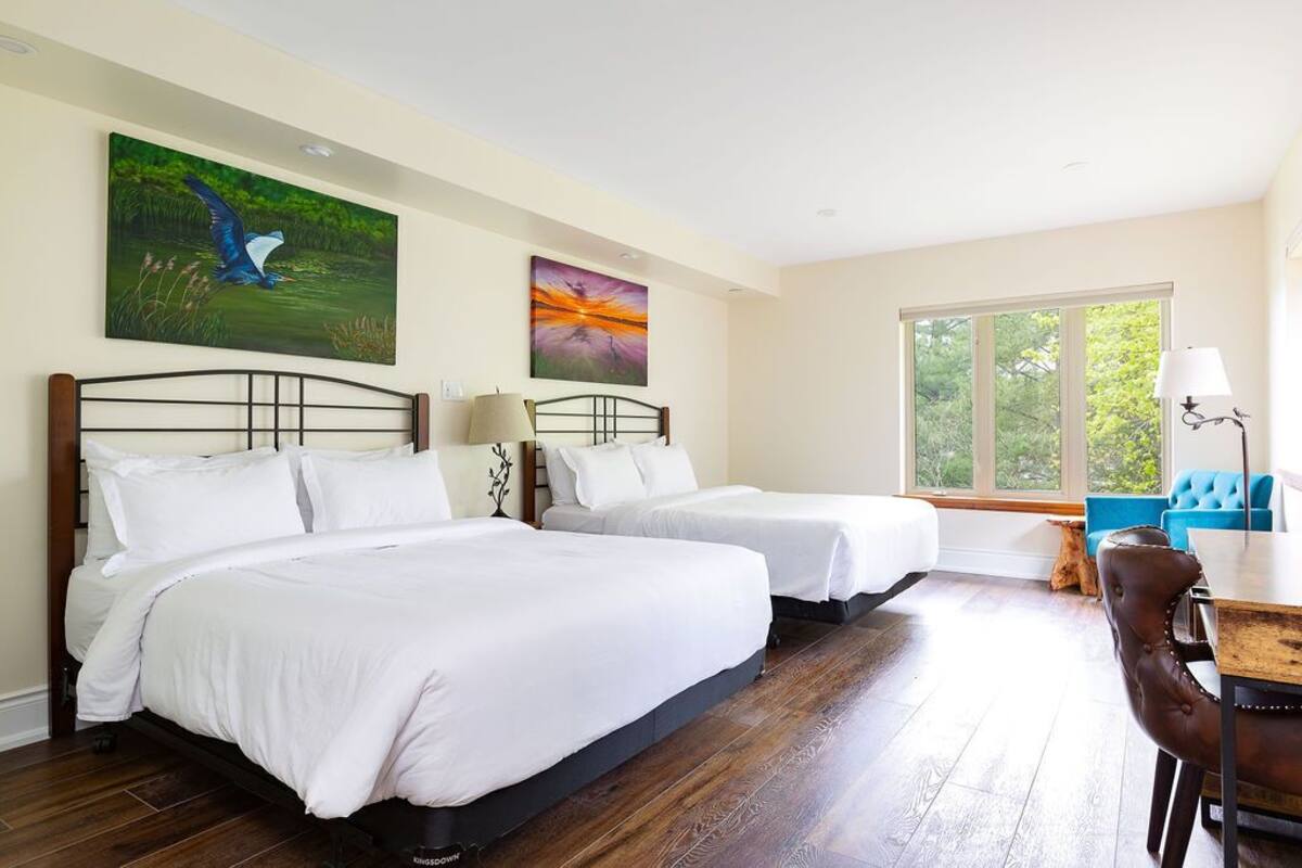 Una habitación de hotel con dos camas, un escritorio y un ventanal amplio.