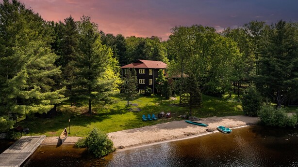 A lakeside cabin with a dock, surrounded by dense forest. - Fairy Bay Lakehouse (Huntsville)