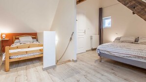 Un dormitorio con dos camas, vigas de madera, una puerta blanca y una ventana.