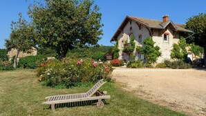 A house with a garden, a wooden bench, and a dirt path.
