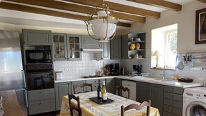 A kitchen with grey cabinets, a microwave, stove, and a dining table with chairs.