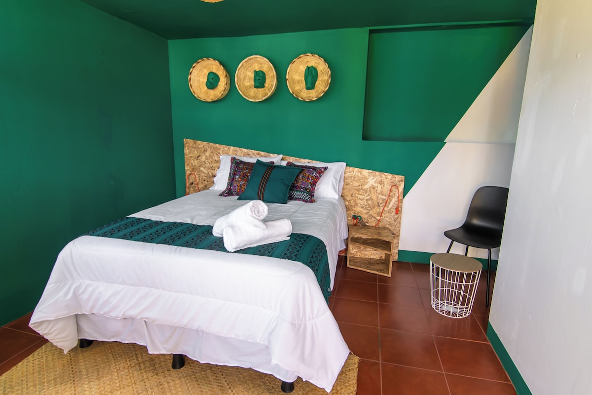 A bedroom with a bed, a chair, a small table, and a wall with three circular decorations.