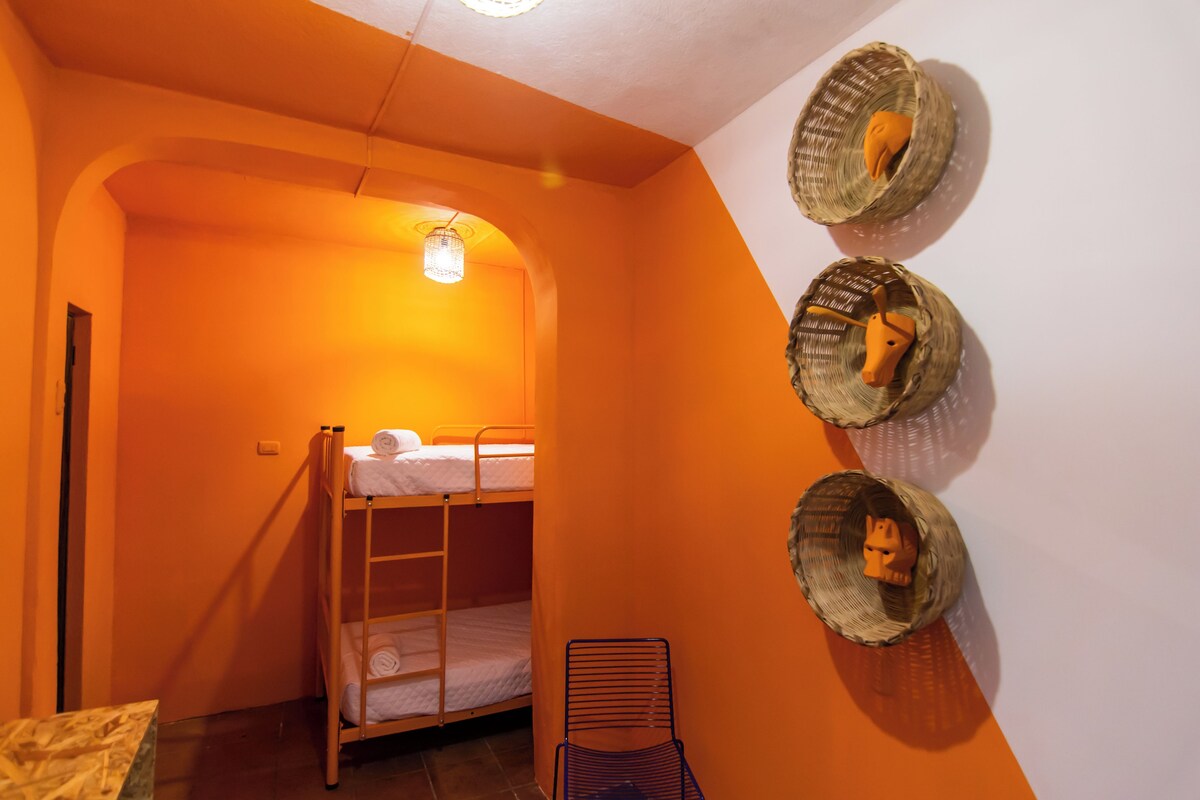 A bunk bed room with a sloped ceiling and a small table.