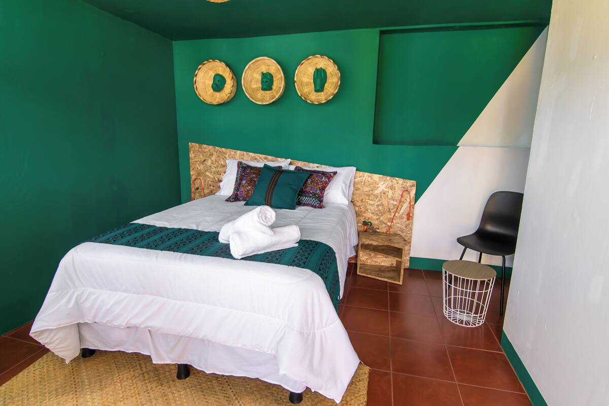 A bedroom with a bed, a chair, a small table, and a wall with three circular decorations.