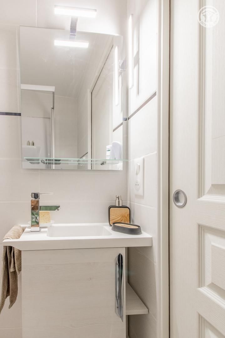 A modern bathroom with a white sink, a mirror, and a towel rack.