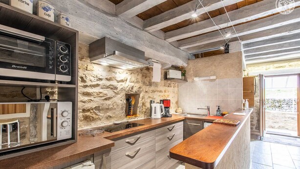 A modern kitchen with a stone wall backsplash, built-in appliances, and a wooden countertop. - Le Verger - Paris L'hopital (PARIS L'HOPITAL)