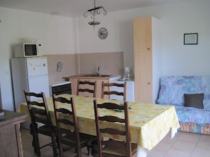 Une cuisine compacte comprenant une table à manger, des chaises, un four à micro-ondes et un réfrigérateur.