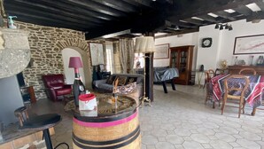 Un interior rústico con pared de piedra, un barril de madera y suelo de baldosas hexagonales.