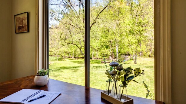 A room with a large window offering a view of a well-maintained garden with trees and grass. - Calm Country Oasis - Creek, ATV Trls & Norris Lake (Speedwell)