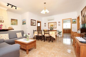 A living room with a sofa, coffee table, dining table with chairs, and a TV. - Delightful three bedroom villa with heated pool (Pollensa / Pollença)