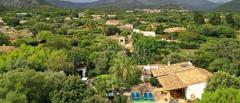 En villa med swimmingpool omgivet af frodig vegetation og bjerge i baggrunden.