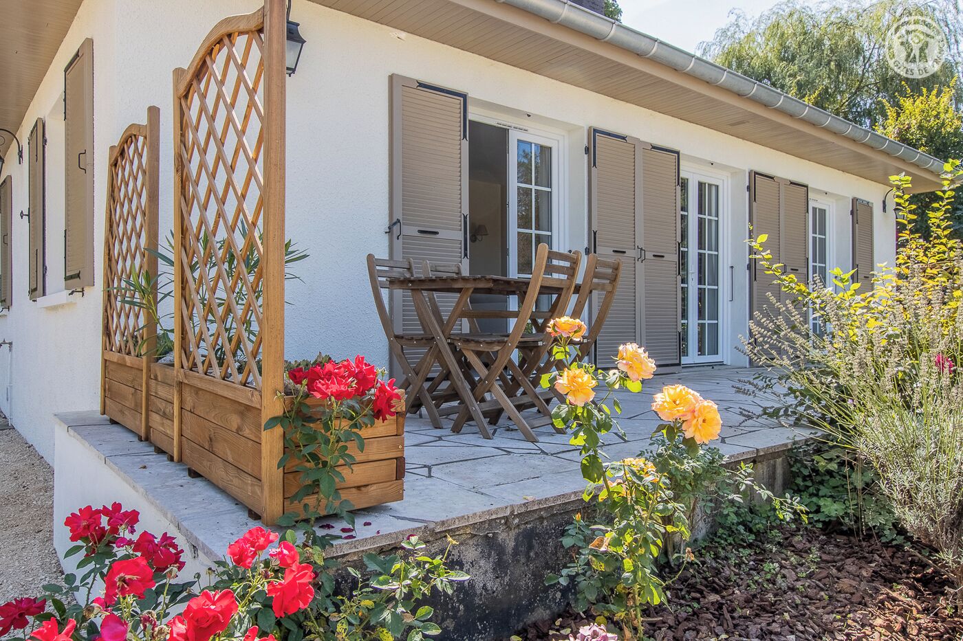 Une maison avec un patio couvert, des chaises en bois et une table.