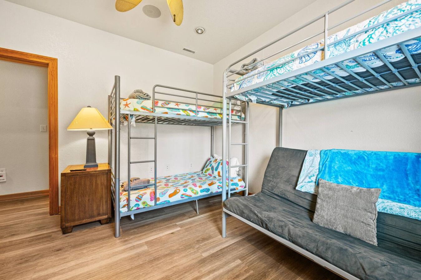 Ett rum med en våningssäng, en soffa, en lampa och ett litet bord i trä.