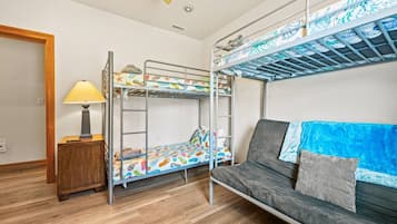 Quarto com beliche, sofá, luminária e mesa de cabeceira de madeira.