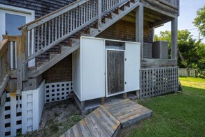 A wooden staircase leading to a deck with a white storage unit and a small wooden platform.