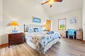 A bedroom with a bed, nightstands, a desk, and a chair.