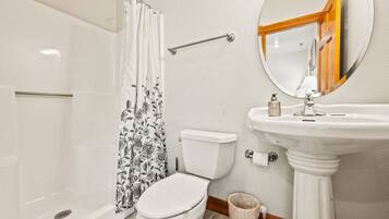 Ein Badezimmer mit Dusche, Toilette, Waschbecken und Spiegel.