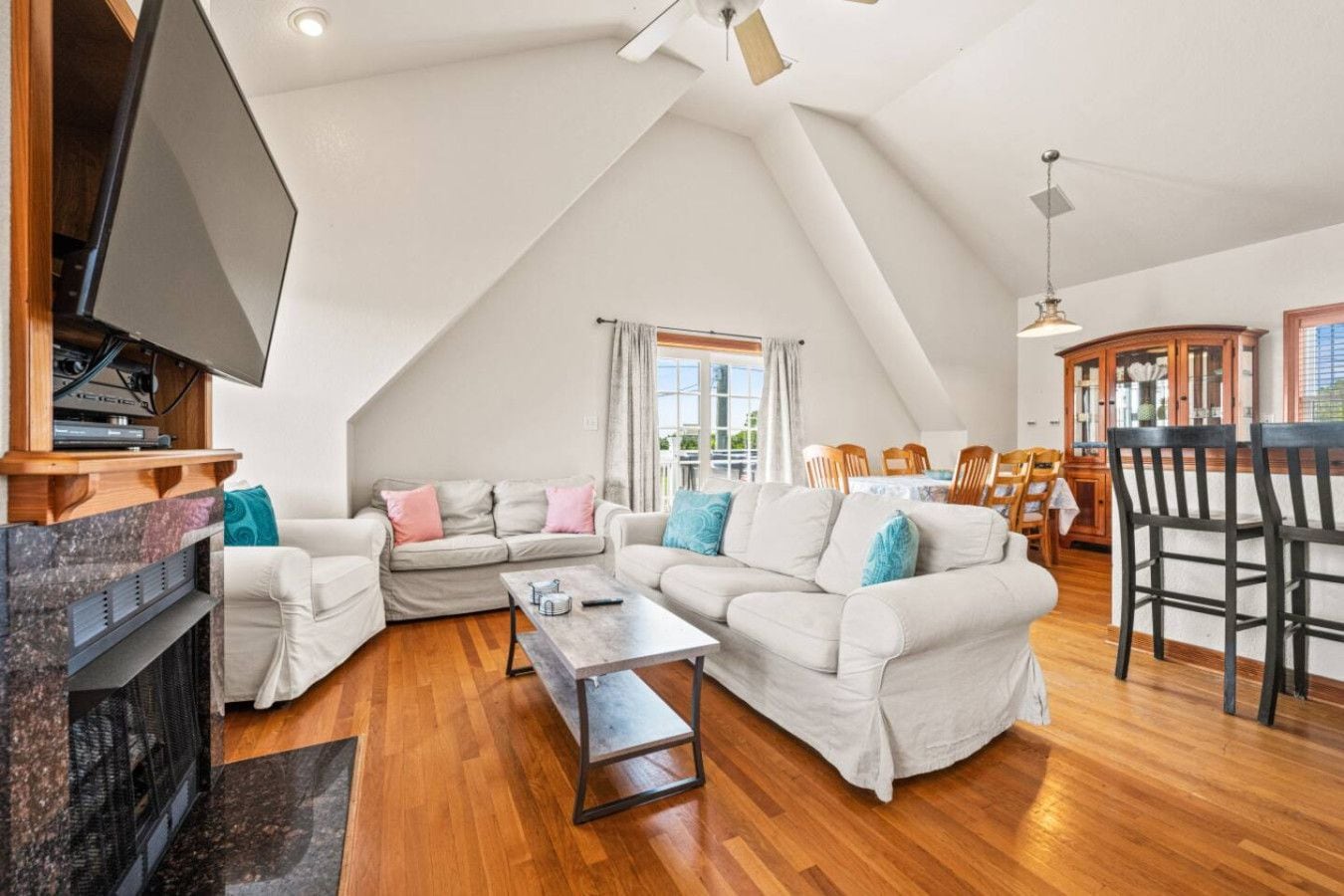 Un vaste espace de vie aménagé dans un style loft, avec un plafond haut, une cheminée, un téléviseur et un coin repas comprenant des chaises et une table en bois.