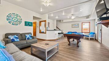 Sala de estar com mesa de bilhar, sofá e mesa de centro.