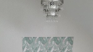 Een hotelkamer met een bed, twee nachtkastjes, een kroonluchter en een bekeken hoofdeinde.
