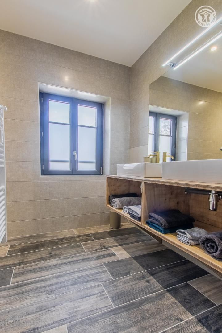 Un baño moderno con dos lavamanos, un espejo grande y una ventana.