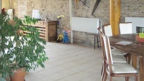A rustic dining area with a stone wall, wooden beams, and a table with chairs.