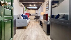 Un salon moderne avec un canapé gris, un coin repas et une cuisine en arrière-plan.