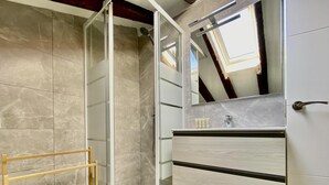 Une salle de bain moderne avec une douche à parois de verre, une échelle en bois et un meuble-lavabo avec un miroir.