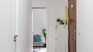 A hallway with a white door, a wooden door, and a shelf with plants.