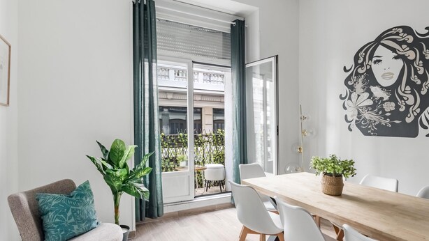 A modern living room with a dining area, large windows, and a city view.