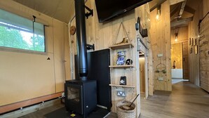Une pièce chaleureuse avec un poêle à bois, une fenêtre et une étagère où sont disposés divers objets.