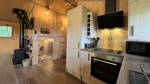 Une cuisine compacte avec des meubles en bois, un four à micro-ondes encastré et une cuisinière.