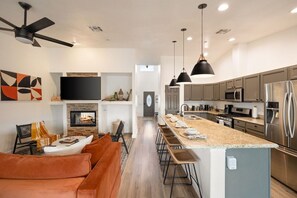 A modern kitchen with a central island, stainless steel appliances, and pendant lighting.