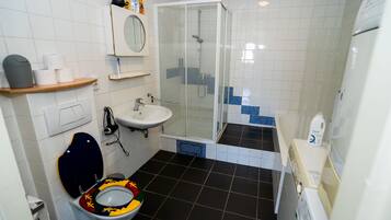 A bathroom with a toilet, sink, shower, and a mirror.