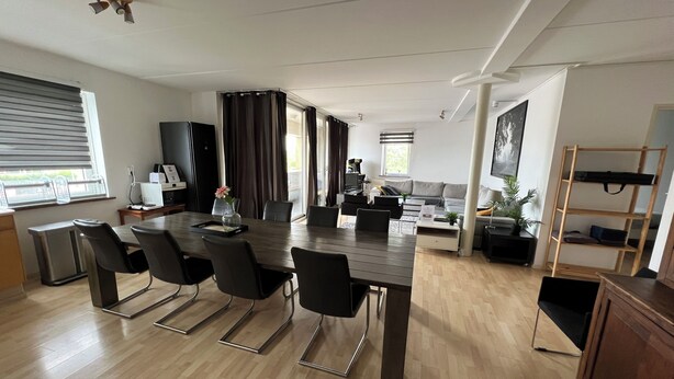 A modern living room with a dining area, large windows, and a flat-screen TV. - Zaanse Schans Apartments (Wormer)