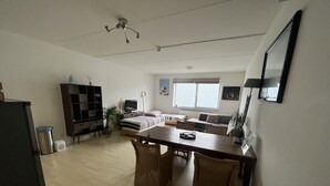 A modern living room with a dining area, a sofa set, and a TV. - Zaanse Schans Apartments (Wormer)