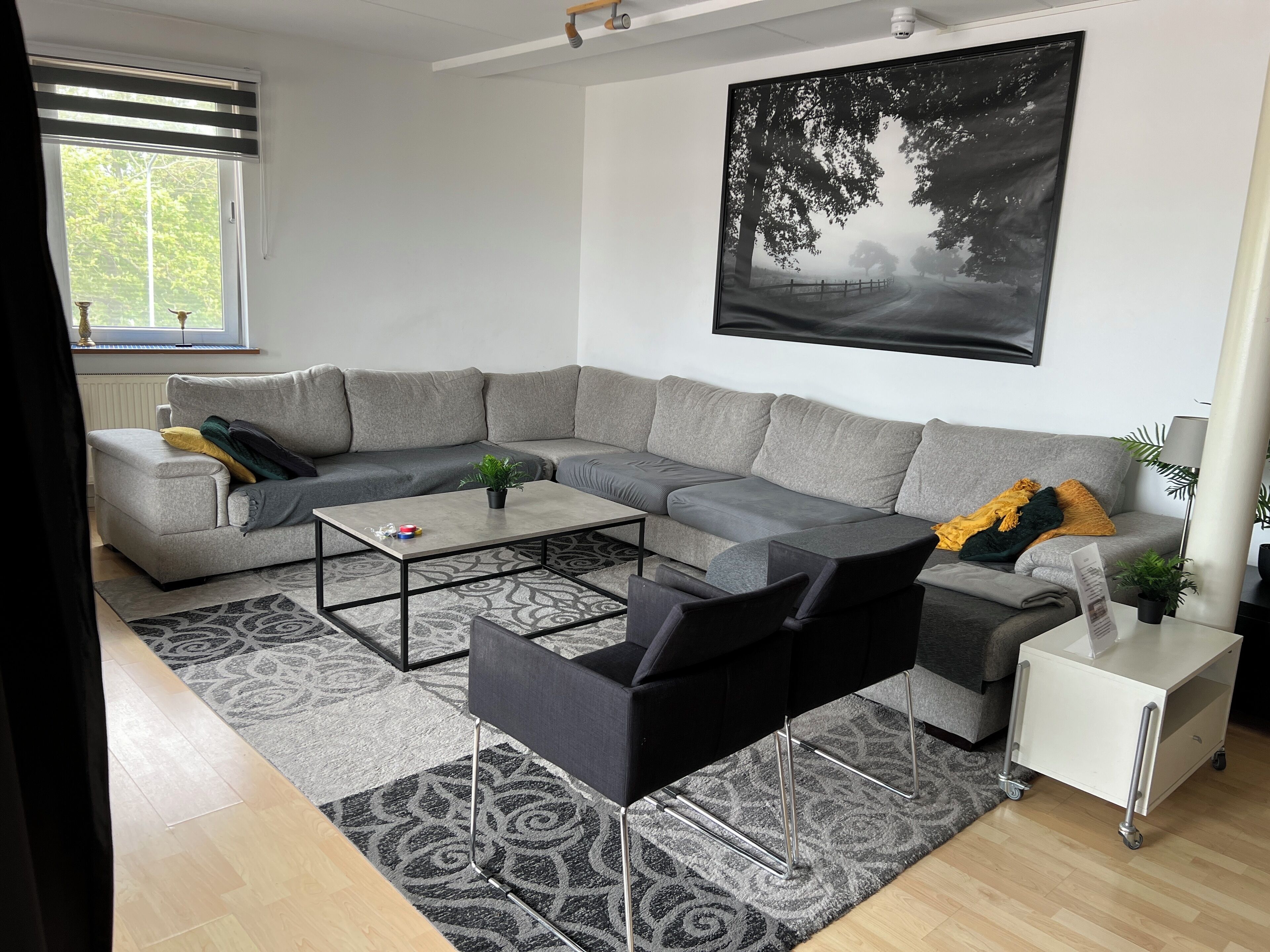 A modern living room with a grey sectional sofa, a black armchair, a coffee table, and a small white side table.