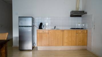 A kitchen with a stainless steel refrigerator, wooden cabinets, a gas stove, and a sink.