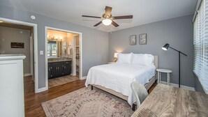 Une chambre à coucher avec un lit, un ventilateur de plafond, un bureau et une chaise.