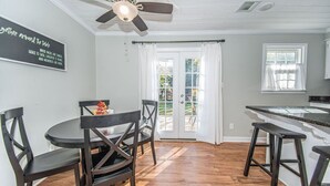 Un coin repas comprenant une table ronde, quatre chaises et un ventilateur de plafond.