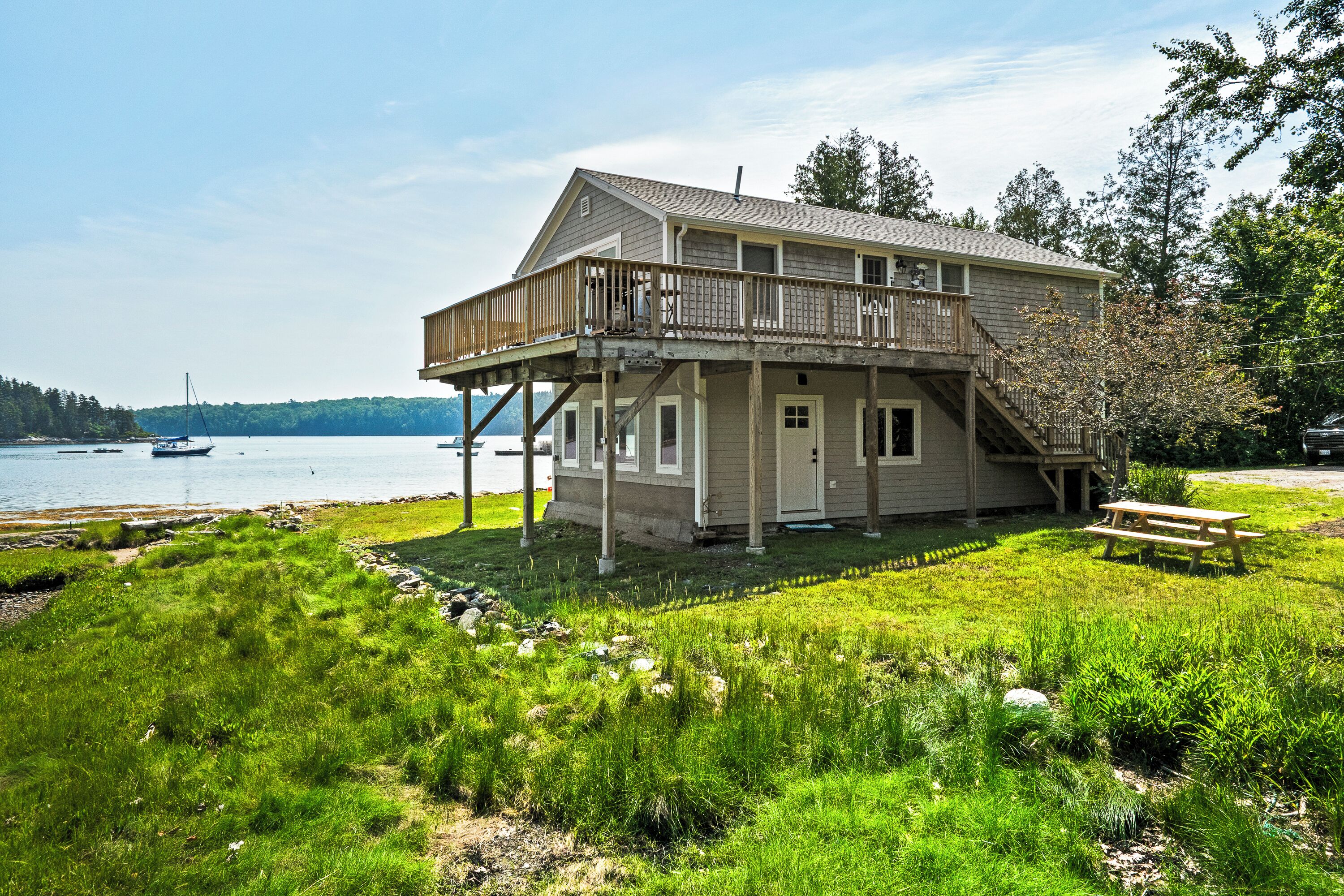 A two-story house with a balcony, located near a body of water.