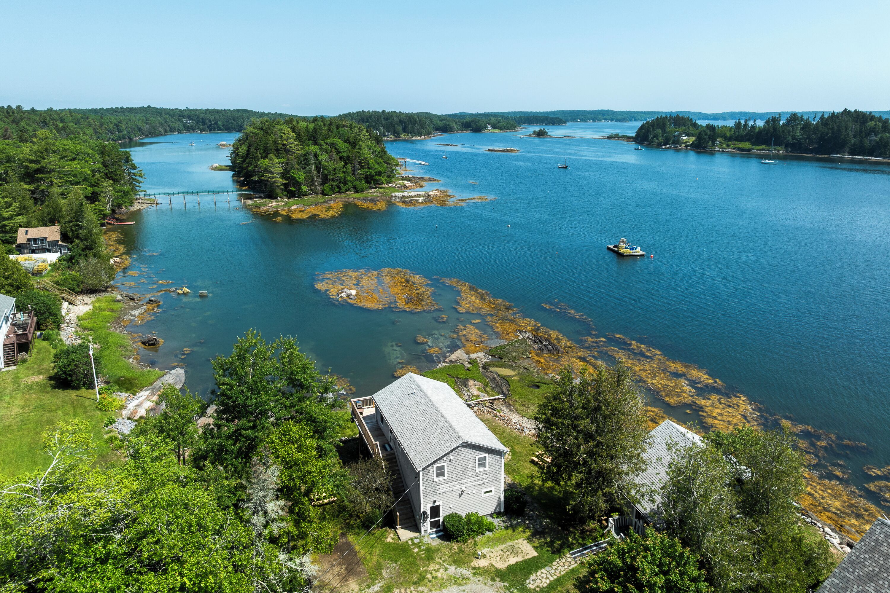 A house with a dock extending into a lake surrounded by dense forest.