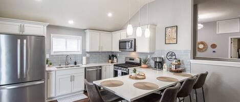A modern kitchen with white cabinets, stainless steel appliances, and a central island with bar stools.
