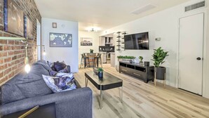 Un salon moderne avec un canapé gris, une table basse et un téléviseur fixé au mur.