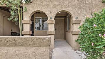 A building with two arched doorways, a small outdoor seating area, and a pathway leading to the entrance.